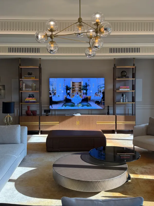 A suite living room with a globe chandelier, a round coffee table and built-in shelves.